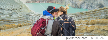 BANNER, LONG FORMAT Young tourist man and woman sit at the edge of the crater of the Ijen volcano or Kawah Ijen on the Indonesian language. Famous volcano containing the biggest in the world acid lake BANNER, LONG FORMAT Young tourist man and woman sit at the edge of the crater of the Ijen volcano or Kawah Ijen on the Indonesian language. Famous volcano containing the biggest in the world acid lake 86901769