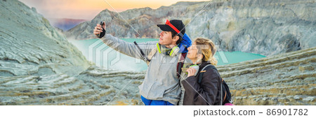BANNER, LONG FORMAT Young tourist man and woman stand at the edge of the crater of the Ijen volcano or Kawah Ijen on the Indonesian language. Famous volcano containing the biggest in the world acid BANNER, LONG FORMAT Young tourist man and woman stand at the edge of the crater of the Ijen volcano or Kawah Ijen on the Indonesian language. Famous volcano containing the biggest in the world acid 86901782