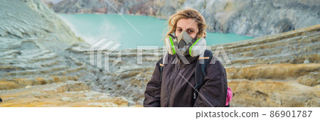 BANNER, LONG FORMAT Young woman tourist sitting at the edge of the crater of the Ijen volcano or Kawah Ijen on the Indonesian language. Famous volcano containing the biggest in the world acid lake and BANNER, LONG FORMAT Young woman tourist sitting at the edge of the crater of the Ijen volcano or Kawah Ijen on the Indonesian language. Famous volcano containing the biggest in the world acid lake and 86901787
