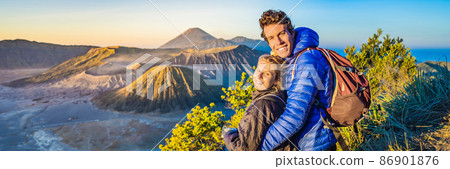 BANNER, LONG FORMAT Young couple man and woman meet the sunrise at the Bromo Tengger Semeru National Park on the Java Island, Indonesia. They enjoy magnificent view on the Bromo or Gunung Bromo on 86901876