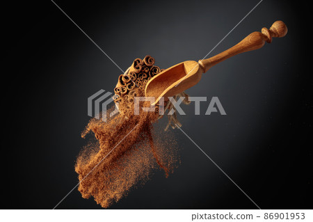 Cinnamon powder is poured out of the wooden spoon. Cinnamon powder is poured out of the wooden spoon. 86901953