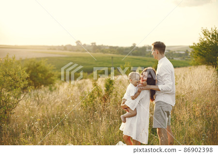 Mother, father and son in white clothes walking on the field Mother, father and son in white clothes walking on the field 86902398