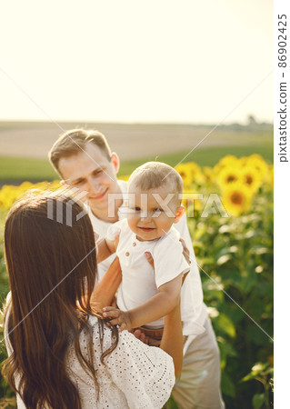 Mother, father and son in white clothes at the sunflowers field Mother, father and son in white clothes at the sunflowers field 86902425