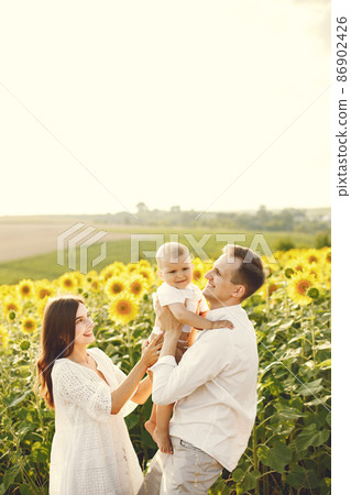 Mother, father and son in white clothes at the sunflowers field Mother, father and son in white clothes at the sunflowers field 86902426