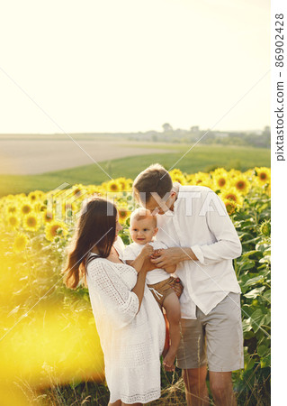 Mother, father and son in white clothes at the sunflowers field 86902428