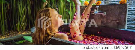 Attractive Young woman in bath with petals of tropical flowers and aroma oils. Spa treatments for skin rejuvenation. Alluring woman in Spa salon. Girl relaxing in bathtub with flower petals. Luxury Attractive Young woman in bath with petals of tropical flowers and aroma oils. Spa treatments for skin rejuvenation. Alluring woman in Spa salon. Girl relaxing in bathtub with flower petals. Luxury 86902567
