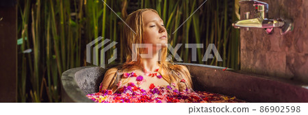 Attractive Young woman in bath with petals of tropical flowers and aroma oils. Spa treatments for skin rejuvenation. Alluring woman in Spa salon. Girl relaxing in bathtub with flower petals. Luxury Attractive Young woman in bath with petals of tropical flowers and aroma oils. Spa treatments for skin rejuvenation. Alluring woman in Spa salon. Girl relaxing in bathtub with flower petals. Luxury 86902598
