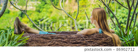 Bali trend, straw nests everywhere. Young tourist enjoying her travel around Bali island, Indonesia. Making a stop on a beautiful hill. Photo in a straw nest, natural environment. Lifestyle BANNER 86902712
