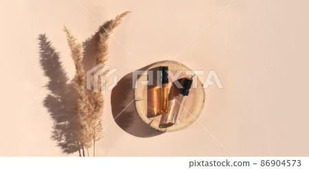 Banner of two Perfume samples with yellow liquid on wooden tray on beige background with pampas grass. Luxury and natural cosmetics presentation. Tester on woodcut in the sunlight. Shades and lights 86904573