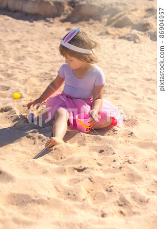 Cute girl playing with easter eggs on the beach  86904957