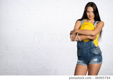 A young girl hugs a yellow construction protective helmet against her chest. With a smile it reminds you of safety during work. A young girl hugs a yellow construction protective helmet against her chest. With a smile it reminds you of safety during work. 86905784
