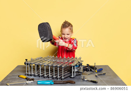 Cute little boy, child in image of auto mechanic or fitter in dungarees with work tools repairing auto motor isolated on yellow background. 86906051