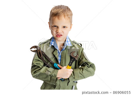 Emotional little boy, cute kid in image of auto mechanic or fitter in green dungarees with work tools isolated over white studio background. Childhood, education concept Emotional little boy, cute kid in image of auto mechanic or fitter in green dungarees with work tools isolated over white studio background. Childhood, education concept 86906055