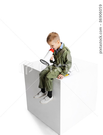 One little boy, cute kid in image of auto mechanic or fitter in green dungarees with work tools sitting on big box isolated over white studio background. One little boy, cute kid in image of auto mechanic or fitter in green dungarees with work tools sitting on big box isolated over white studio background. 86906059