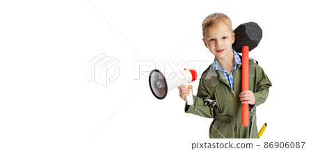 Shouting at megaphone. Little boy, cute kid in image of auto mechanic or fitter in green dungarees with work tools isolated over white studio background. Childhood, education concept 86906087