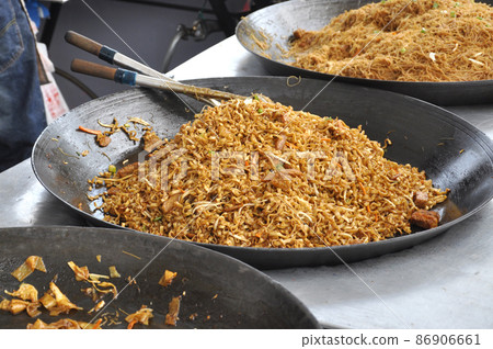 Malaysian street food Mee Dulang. Noodles are cooked in large pans in large quantities at the night market or on the street. Sold in packages at a cheap price. Malaysian street food Mee Dulang. Noodles are cooked in large pans in large quantities at the night market or on the street. Sold in packages at a cheap price. 86906661