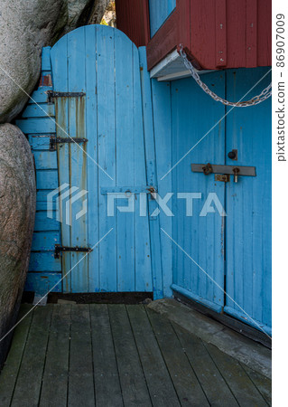 An old blue wooden door next to a rock formation An old blue wooden door next to a rock formation 86907009