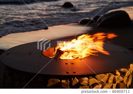 The beautiful metal round a fireplace stands on the sandy coast with a tidal wave at sunset, stones, sand, waves, the landscape, tranquillity, the sun falls, firewood, nobody The beautiful metal round a fireplace stands on the sandy coast with a tidal wave at sunset, stones, sand, waves, the landscape, tranquillity, the sun falls, firewood, nobody 86908711