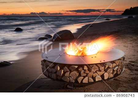 The beautiful metal round a fireplace stands on the sandy coast with a tidal wave at sunset, stones, sand, waves, the landscape, tranquillity, the sun falls, firewood, nobody The beautiful metal round a fireplace stands on the sandy coast with a tidal wave at sunset, stones, sand, waves, the landscape, tranquillity, the sun falls, firewood, nobody 86908743