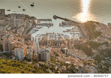 Aerial view of the Principality of Monaco at sunrise, Monte-Carlo, old town, view point in La Turbie at morning, port Hercule, Prince Palace, Mountains, Megayachts, a lot of boats, sun reflection Aerial view of the Principality of Monaco at sunrise, Monte-Carlo, old town, view point in La Turbie at morning, port Hercule, Prince Palace, Mountains, Megayachts, a lot of boats, sun reflection 86908757