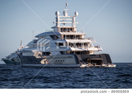 The boat stern of huge yacht in sea at sunny day, glossy board of the motor boat, the chrome plated handrail, megayacht is moored in harbour, sun reflection on glossy board 86908869