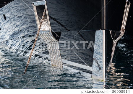 The mesmerizing reflection of the water on the glossy side of a huge yacht anchored, chrome details, chains and ropes to the muring descend into the water The mesmerizing reflection of the water on the glossy side of a huge yacht anchored, chrome details, chains and ropes to the muring descend into the water 86908914