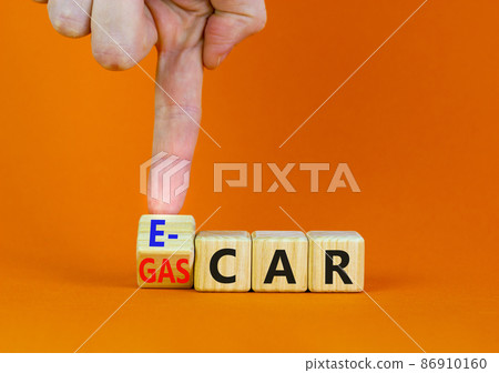 Gas car or e-car symbol. Businessman turns a wooden cube and changes words Gas car to E-car. Beautiful orange table orange background, copy space. Business and gas or electric car E-car concept. 86910160