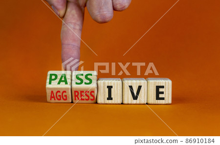 Passive or aggressive symbol. Businessman turns wooden cubes and changes the word passive to aggressive. Beautiful orange background, copy space. Business, psychological passive aggressive concept. Passive or aggressive symbol. Businessman turns wooden cubes and changes the word passive to aggressive. Beautiful orange background, copy space. Business, psychological passive aggressive concept. 86910184