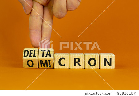 Covid-19 omicron or deltacron symbol. Doctor turns cubes and changes the word omicron to deltacron. Beautiful orange background. Medical, covid-19 corona omicron or deltacron concept. Copy space. 86910197
