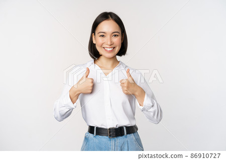 Image of beautiful adult asian woman showing thumbs up, wearing formal office, university clothing, recommending company, standing over white background Image of beautiful adult asian woman showing thumbs up, wearing formal office, university clothing, recommending company, standing over white background 86910727