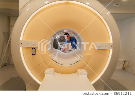 installer engineer of mri apparatus in scanner with instructions in hand 86911211