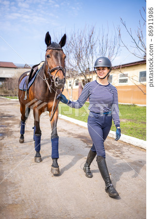 Young jockey teen girl walking with the horse before training 86911986