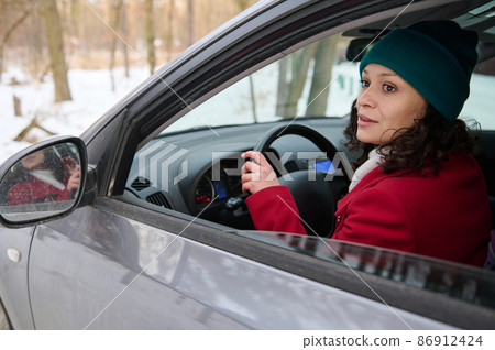 Portrait of a confident African American woman traveler driver, driving car in a snow-covered woodland. Portrait of a confident African American woman traveler driver, driving car in a snow-covered woodland. 86912424