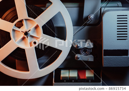Coils with tape film turning. Analog player. Retro old-fashioned 8mm projector playing movie at 86915734