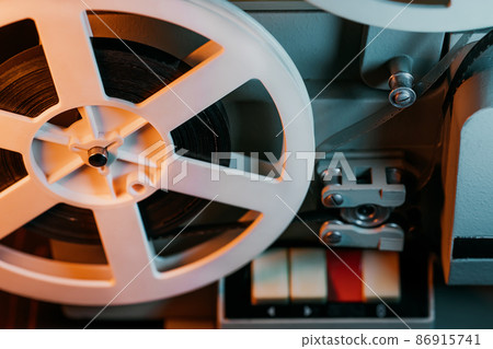 Bobbin film turning. Analog player. Retro old-fashioned 8mm projector playing movie at home theater Bobbin film turning. Analog player. Retro old-fashioned 8mm projector playing movie at home theater 86915741