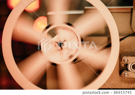 8mm movie projector playing at theater. White reel or can with tape film turning. Analog player 86915745