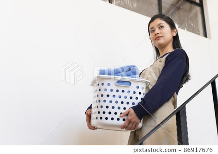 一名年輕女子拿著洗衣籃下樓(管家、家政機構、管家) 一名年輕女子拿著洗衣籃下樓(管家、家政機構、管家) 86917676