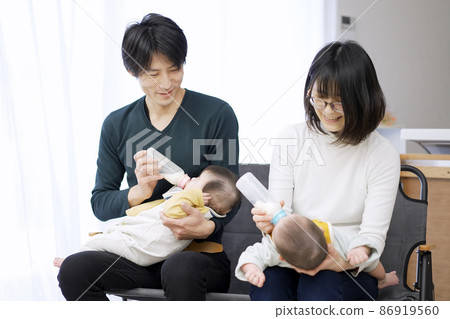 Asian parents feeding twin babies milk 86919560