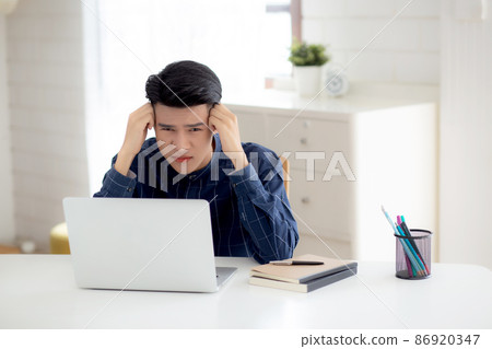 Young asian business man headache during working on laptop computer with deadline. 86920347