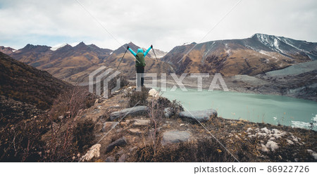 Successful woman backpacker outstretched limbs to fossil glacier on high altitude mountain top Successful woman backpacker outstretched limbs to fossil glacier on high altitude mountain top 86922726
