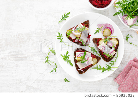 Sandwiches with salted herring fillet and beetroot pate. Top view, overhead Sandwiches with salted herring fillet and beetroot pate. Top view, overhead 86925022