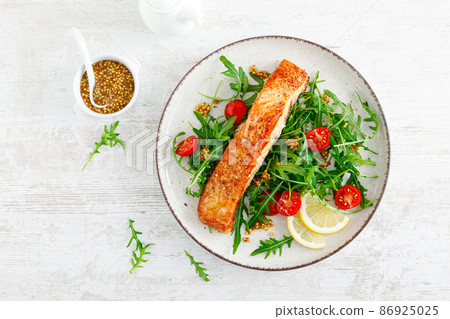 Salmon fish fillet grilled and fresh vegetable tomato salad with arugula. Healthy food. Ketogenic diet. Lunch. Top view Salmon fish fillet grilled and fresh vegetable tomato salad with arugula. Healthy food. Ketogenic diet. Lunch. Top view 86925025