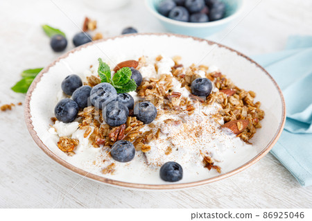 Bowl of granola with fresh blueberry, cottage cheese or curd, yogurt and nuts. Healthy food. Breakfast Bowl of granola with fresh blueberry, cottage cheese or curd, yogurt and nuts. Healthy food. Breakfast 86925046