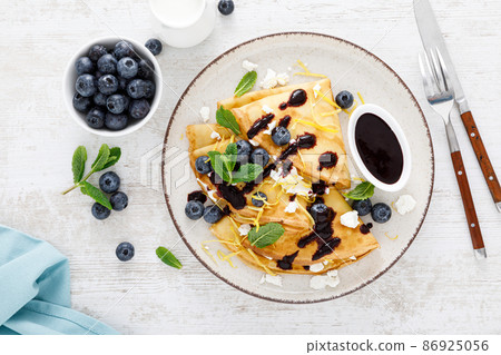 Crepes. Thin pancakes stuffed with cottage cheese and fresh blueberries. Top view 86925056