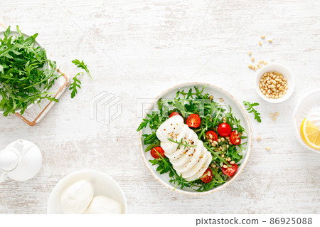 Salad with arugula, mozzarella cheese and pine nuts. Breakfast. Ketogenic, keto or paleo diet. Healthy food. Top view 86925088