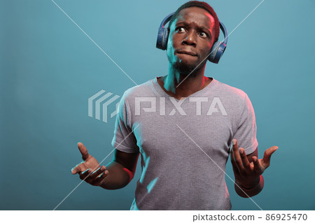 Man with thoughtful expression listening to music on headphones 86925470