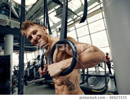 Muscle-up exercise young man doing intense cross fit workout at the gym on gymnastic rings. Muscle-up exercise young man doing intense cross fit workout at the gym on gymnastic rings. 86925555