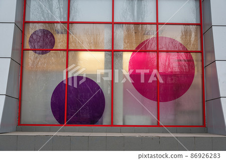 A multicolored mall window display. The architectural composition of glass and metal. Pink and gray circles on the windows. Architecture A multicolored mall window display. The architectural composition of glass and metal. Pink and gray circles on the windows. Architecture 86926283