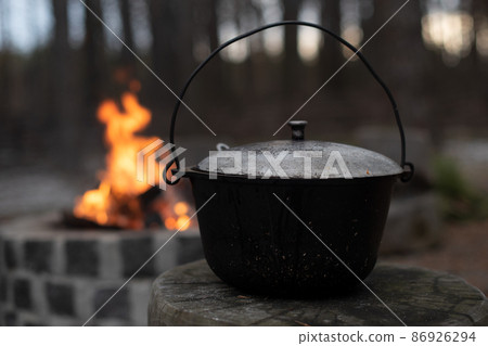 Food in the pot over the fire, tourist camp, preparing food. Camp hot food for tourists in the forest. Food in the pot over the fire, tourist camp, preparing food. Camp hot food for tourists in the forest. 86926294