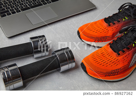 Orange running shoes sneakers, dumbbells and a laptop 86927162